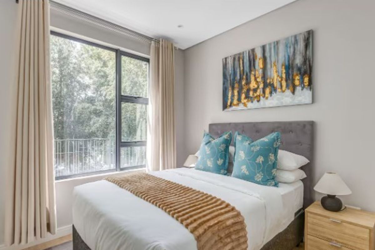 A well-maintained bedroom featuring large windows with natural light, neutral wall finishes, and modern aluminum window frames.