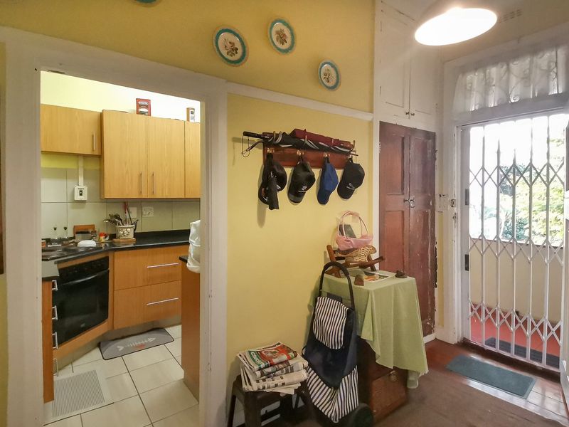 Entryway leading to a compact kitchen with built-in cabinetry, featuring a security gate and built-in storage cupboards.