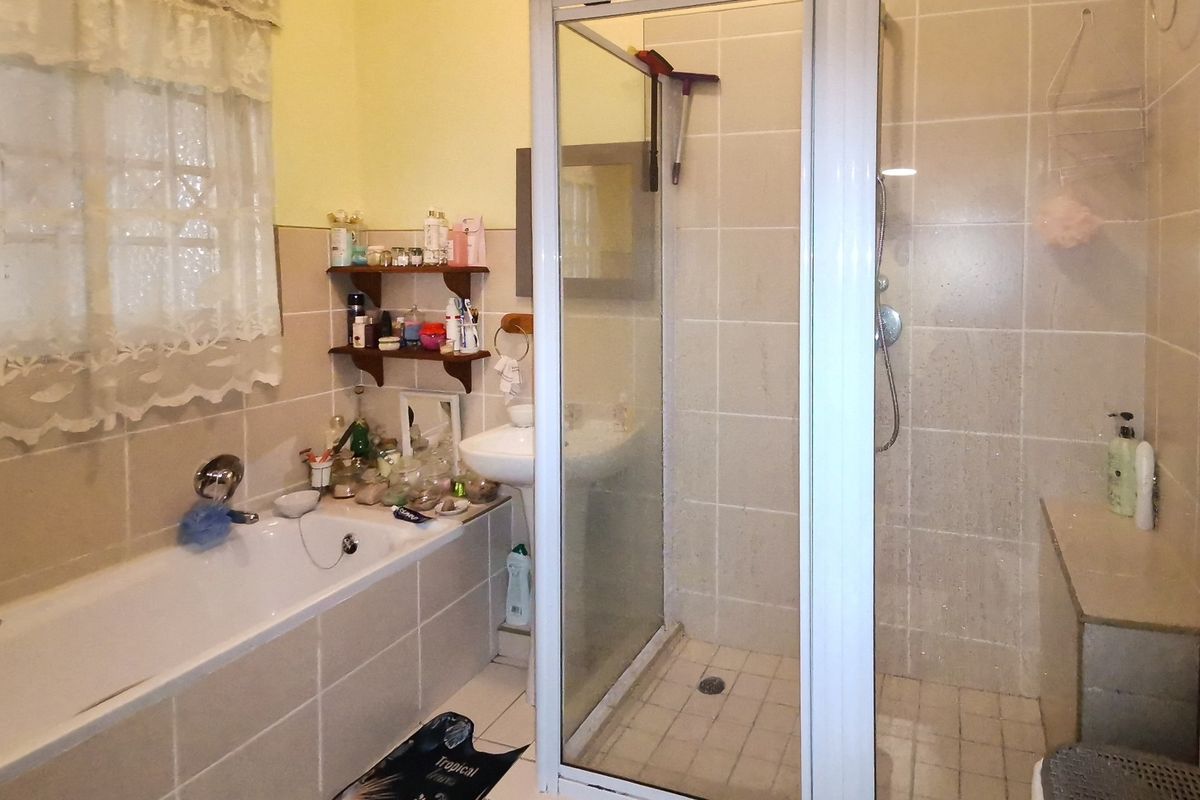 A functional bathroom featuring a bathtub, a separate shower enclosure with glass door, and a pedestal basin with tiled finishes.