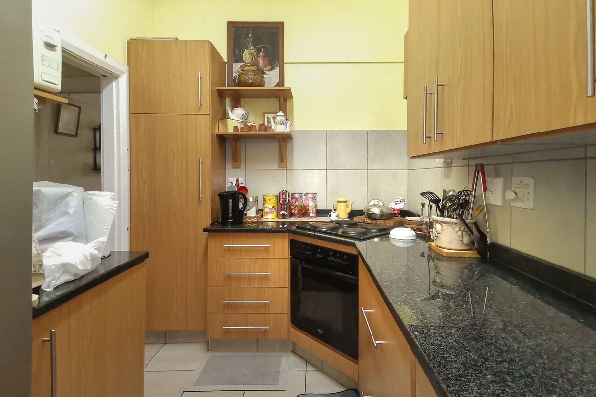 A functional kitchen featuring wood-finish cabinetry, dark granite countertops, a built-in oven, and a tiled backsplash.