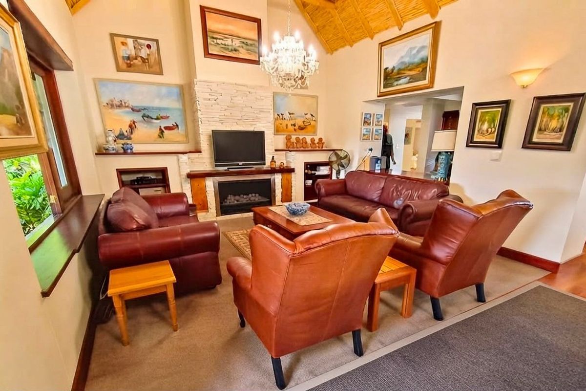 A cozy living room featuring a stone-clad fireplace, vaulted timber ceiling, and warm natural light, creating a welcoming and traditional atmosphere.