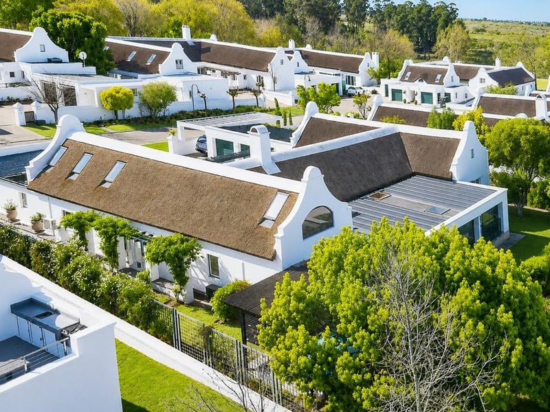 Aerial view of a residential estate featuring traditional Cape Dutch style architecture with thatched roofs, gabled facades, and well-maintained landscaped grounds.