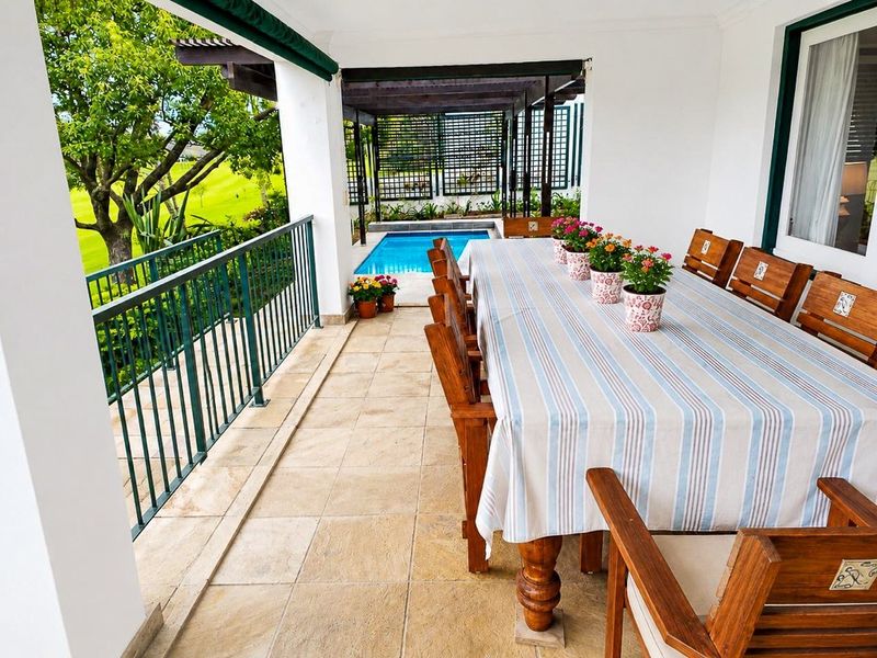 Covered patio area featuring tiled flooring, metal balustrade, and direct access to an outdoor swimming pool and garden views.