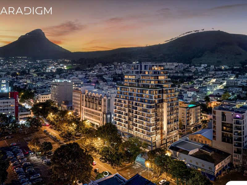Aerial view of The Paradigm apartment building at dusk, showcasing its prominent architectural design within the surrounding urban landscape and mountain backdrop.