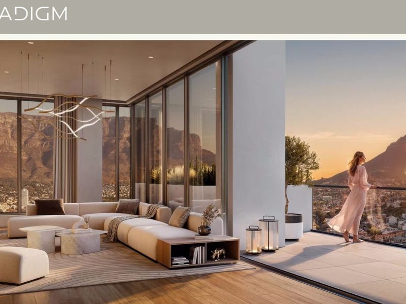 A luxurious open-plan living area featuring floor-to-ceiling glass sliding doors that open onto a spacious balcony with panoramic mountain and city views.