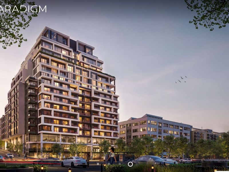 A high-rise apartment building exterior featuring modern architectural design, glass balconies, and integrated street-level commercial spaces.