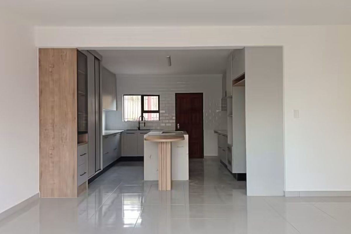 A modern, open-plan kitchen featuring sleek cabinetry, a central island with a breakfast bar, and high-gloss tiled flooring.