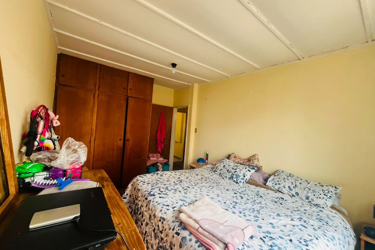 A bedroom featuring built-in wooden wardrobes and a simple ceiling design, offering a functional space with potential for cosmetic updates.