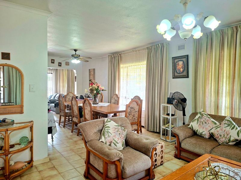 Open plan living and dining area featuring tiled flooring, a ceiling fan, and a decorative chandelier, creating a functional and connected living space.