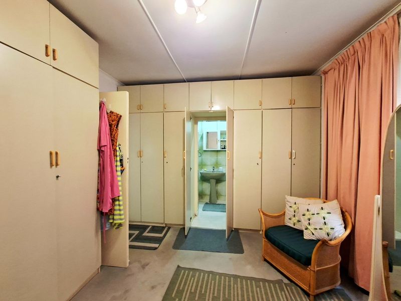 Bedroom featuring extensive built-in floor-to-ceiling cabinetry and direct access to an en-suite bathroom with a pedestal basin.