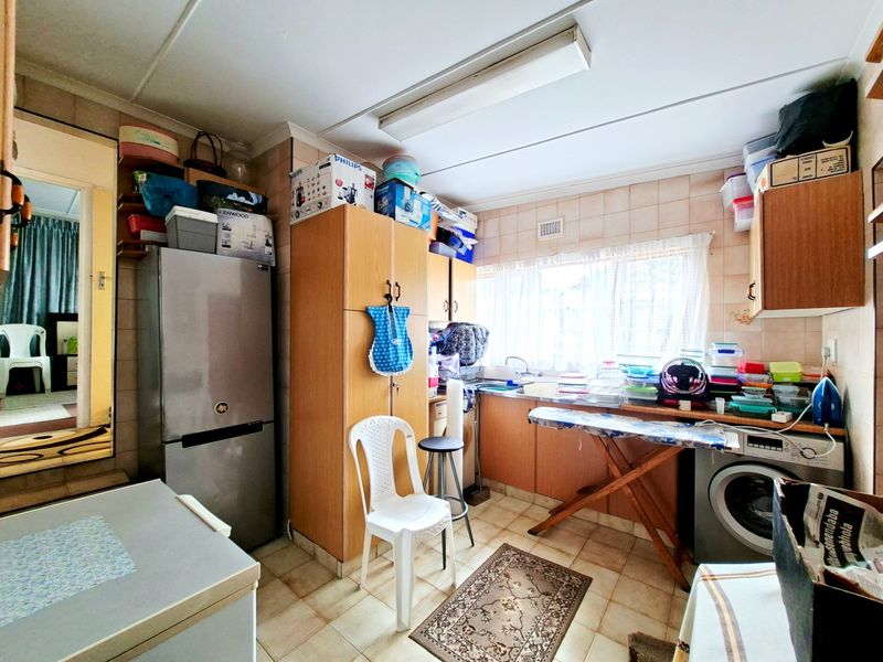 A functional kitchen space featuring tiled walls, built-in cabinetry, and a dedicated laundry area with plumbing for a washing machine.
