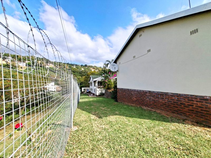 Side garden area featuring a high security wire fence with razor wire topping and a brick-base exterior wall.