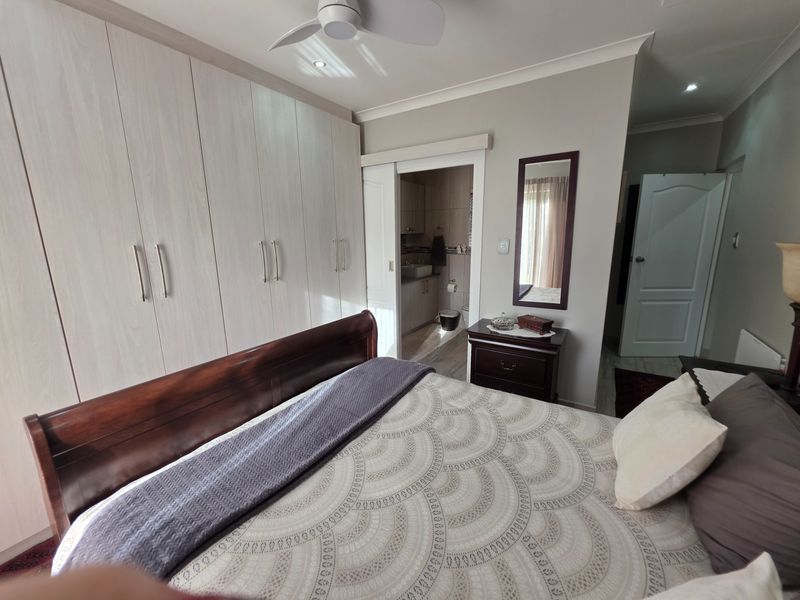 Spacious bedroom featuring extensive built-in cabinetry, a ceiling fan, and an en-suite bathroom access point.