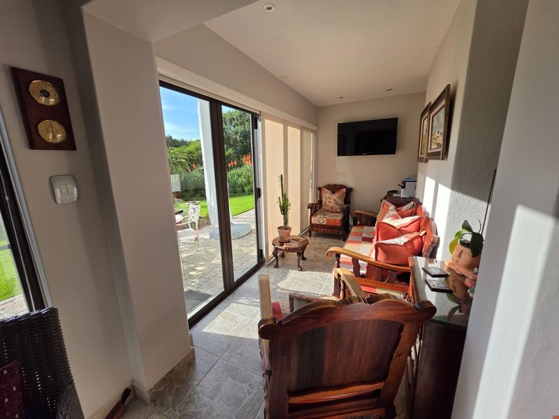 A bright sunroom or living area featuring tiled flooring and large sliding glass doors that provide direct access to the outdoor patio and garden.