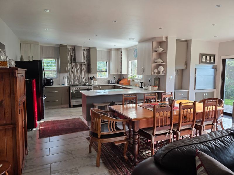 Spacious open-plan kitchen and dining area featuring modern cabinetry, a central breakfast island, and direct access to the outdoor patio.