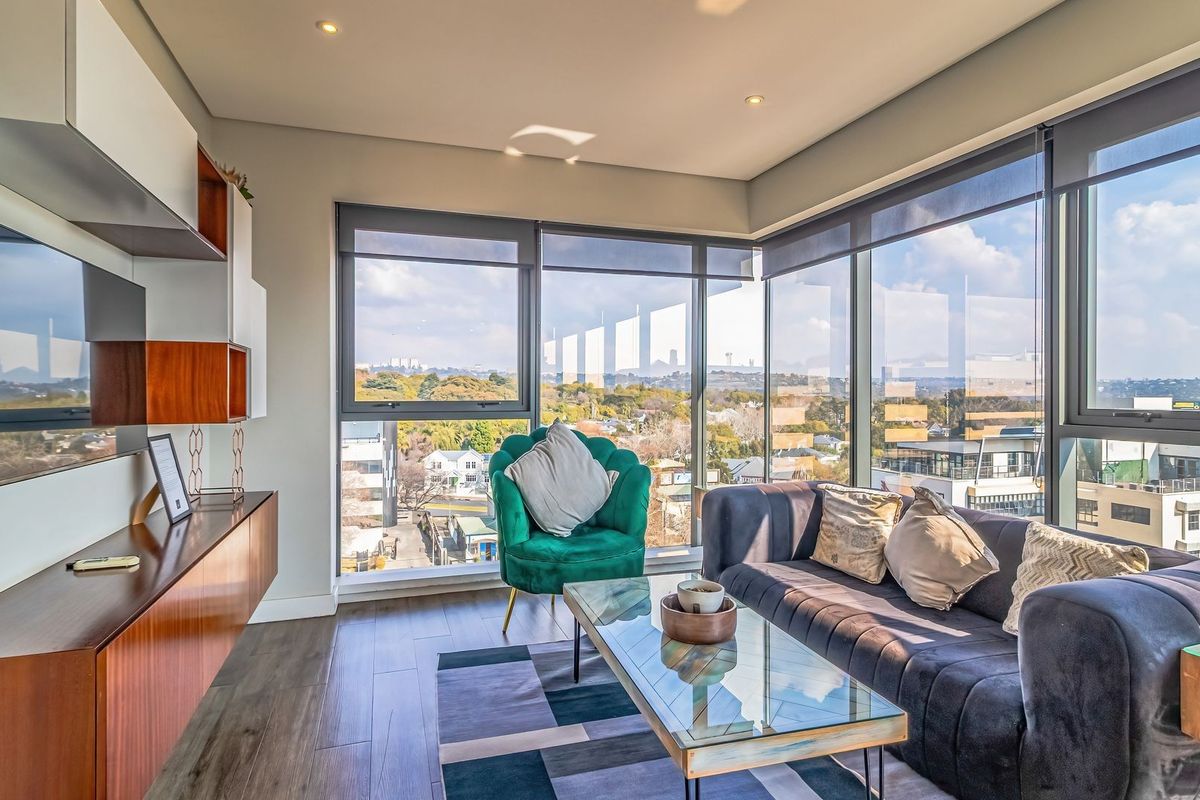 Modern living room featuring floor-to-ceiling windows with expansive urban views, sleek wood-look flooring, and custom built-in cabinetry.