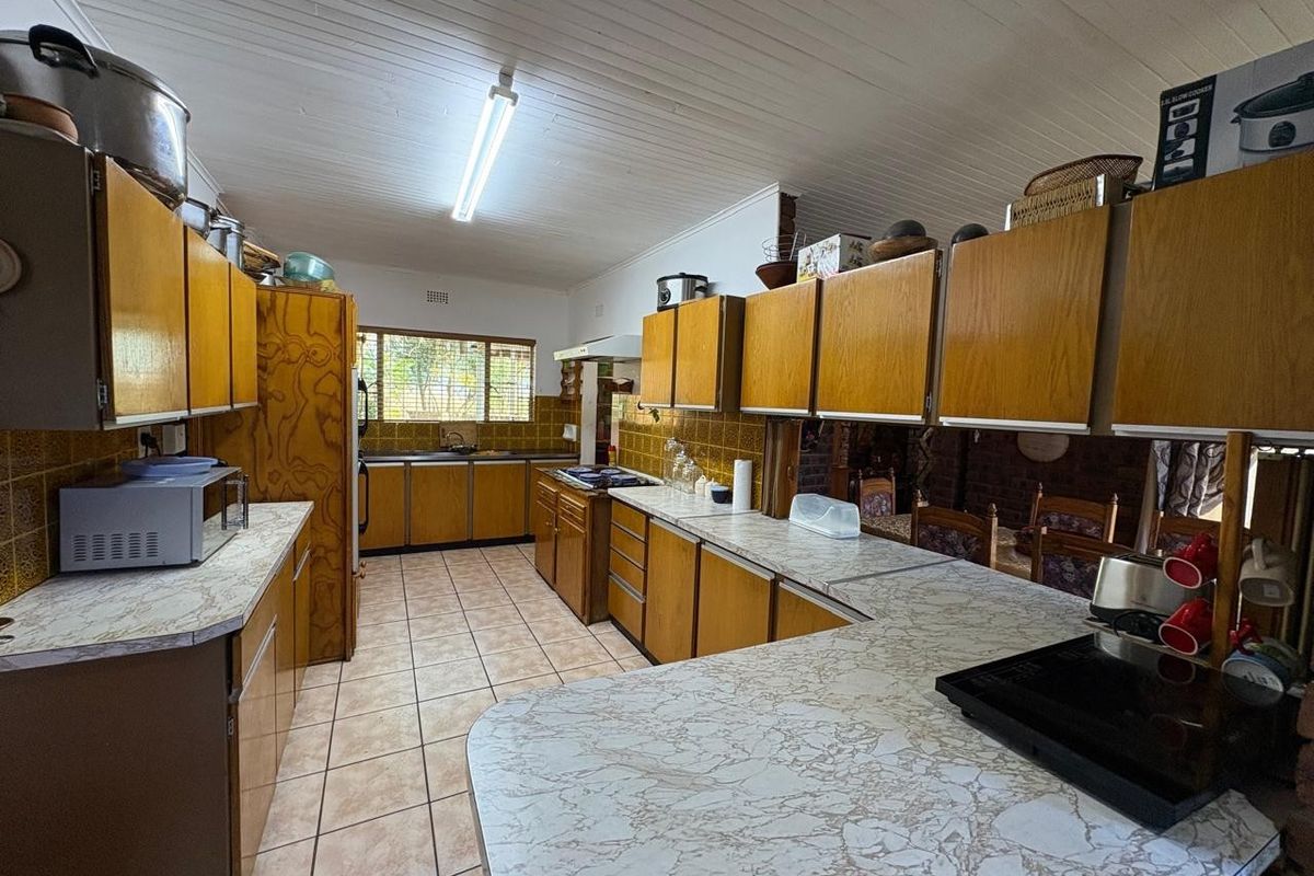 A dated kitchen featuring wood-finish cabinetry, laminate countertops, tiled flooring, and a tongue-and-groove ceiling, offering a functional layout with significant renovation potential.