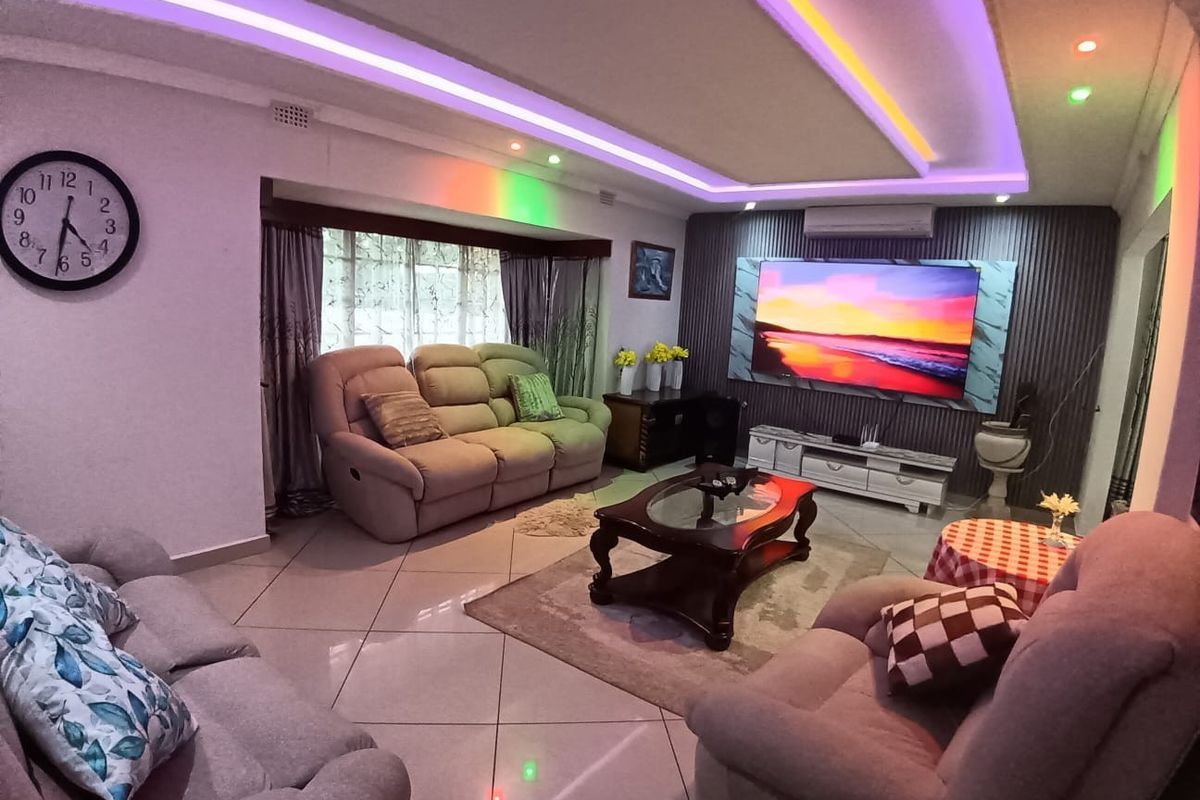 Spacious living room featuring a modern tray ceiling with integrated LED lighting, tiled flooring, and a feature wall with built-in air conditioning unit.