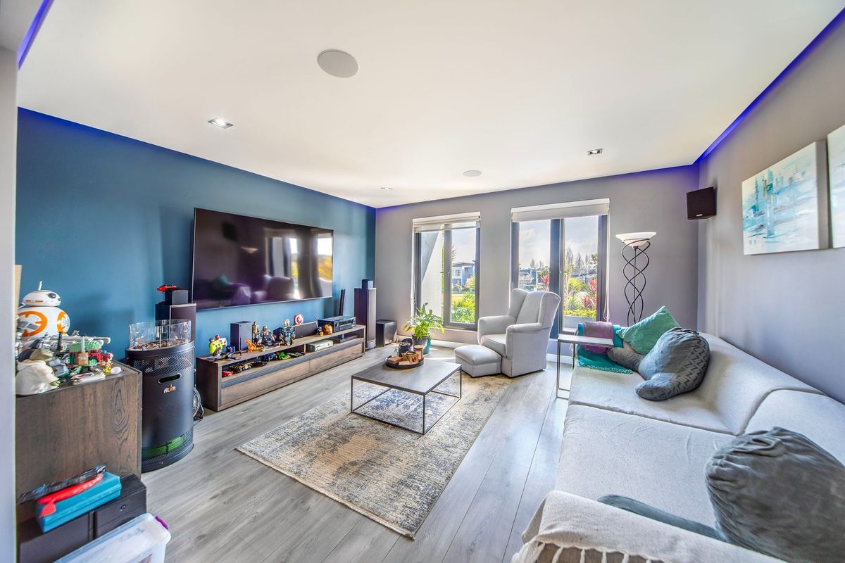 Modern living room featuring recessed ceiling lighting, integrated audio speakers, and large glass doors providing natural light and garden access.