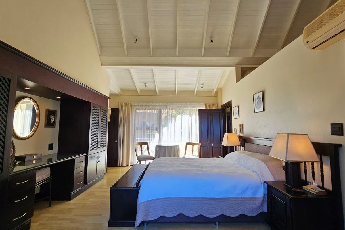 Spacious bedroom featuring high vaulted timber ceilings, built-in cabinetry, and direct access to a private outdoor area through large glass sliding doors.