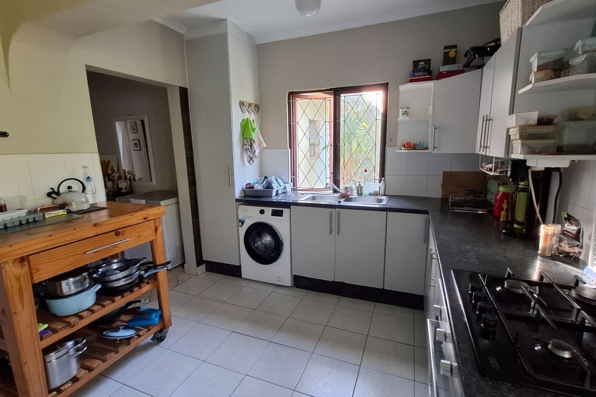 Functional kitchen featuring built-in cabinetry, integrated gas hob, stainless steel sink, and dedicated space for laundry appliances.