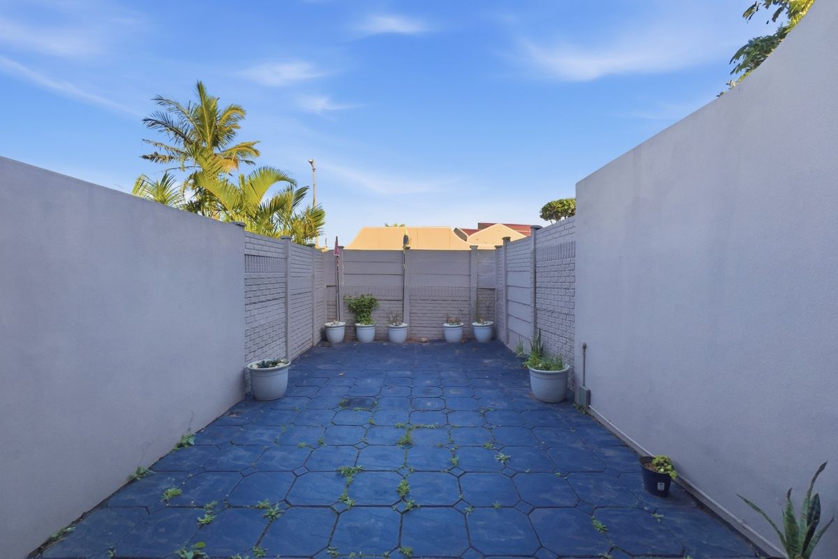 A private, enclosed rear courtyard featuring paved flooring and high perimeter boundary walls, offering a secure outdoor space.