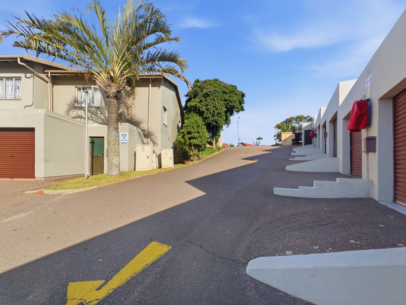 A view of the townhouse complex driveway featuring multiple garage access points and paved common areas.
