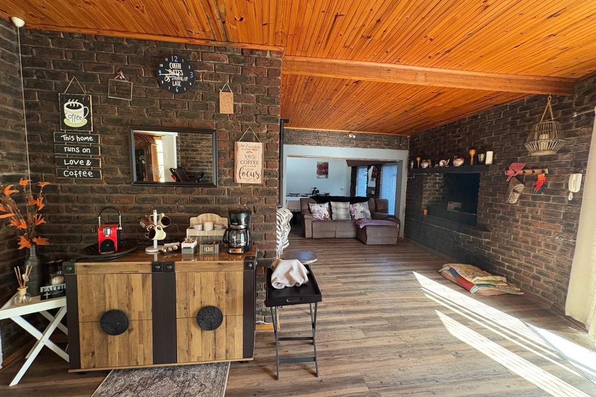 Spacious living area featuring exposed brick walls, timber-clad vaulted ceilings, and a built-in fireplace, creating a rustic and warm atmosphere.