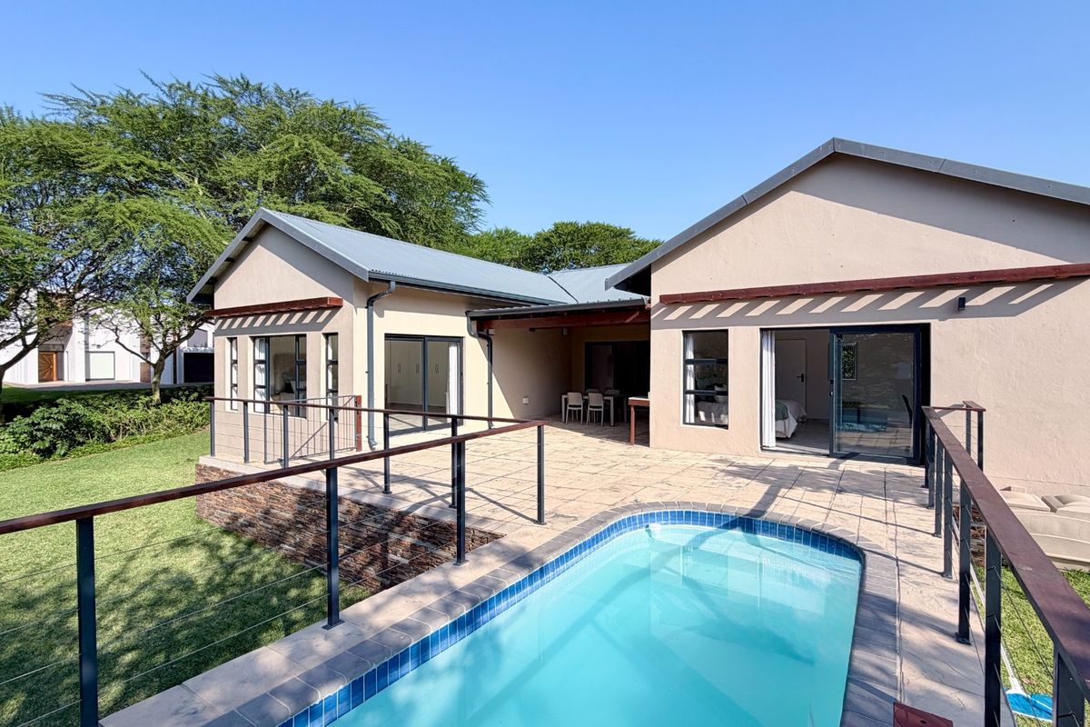 Rear view of the house featuring a paved patio area, a swimming pool with metal railings, and direct access to the interior via sliding doors.
