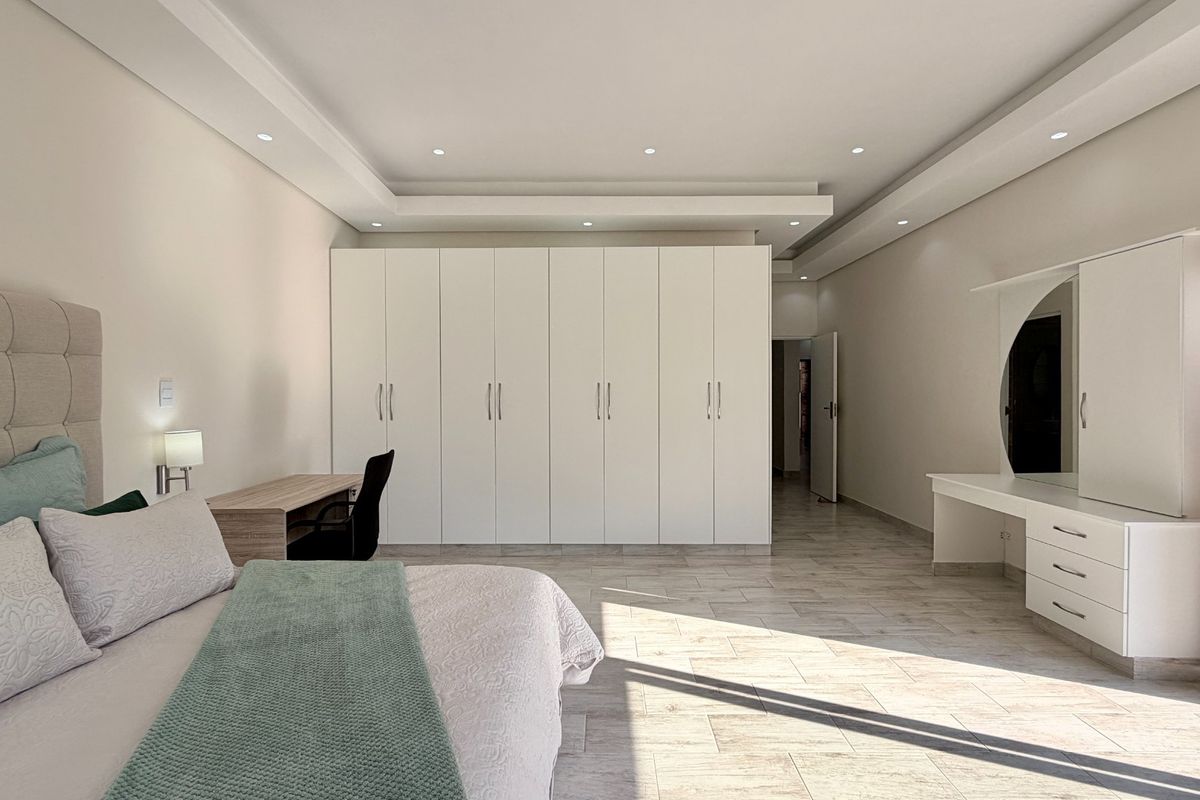 Spacious bedroom featuring extensive built-in cabinetry, recessed ceiling lighting, and tiled flooring, offering a clean and modern aesthetic.