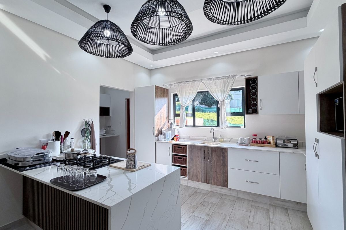 Modern kitchen featuring a central island with a gas hob, stone countertops, and contemporary cabinetry with integrated storage solutions.