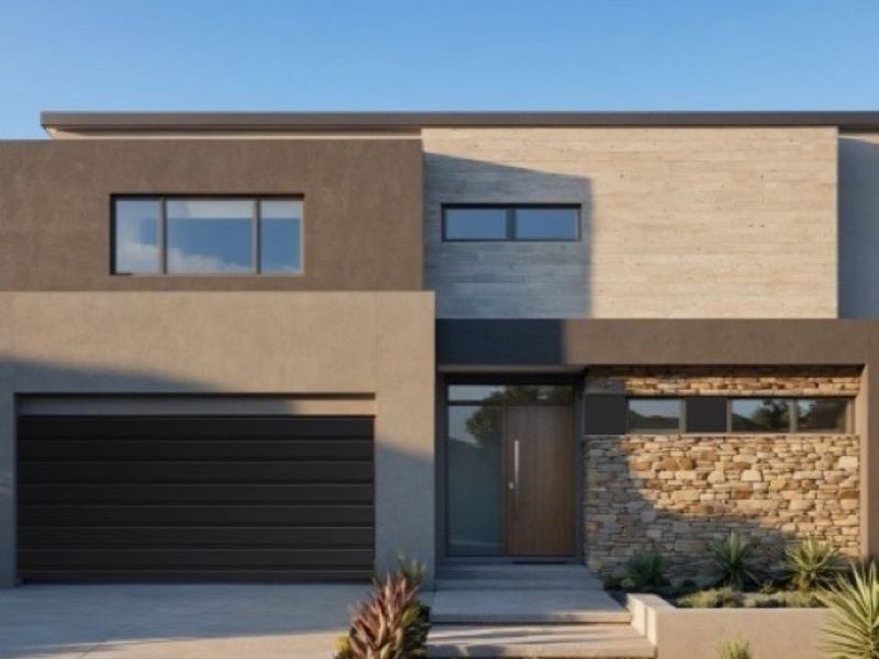 Modern double-story residential facade featuring a combination of stone cladding, rendered walls, and a double garage with a paved driveway.