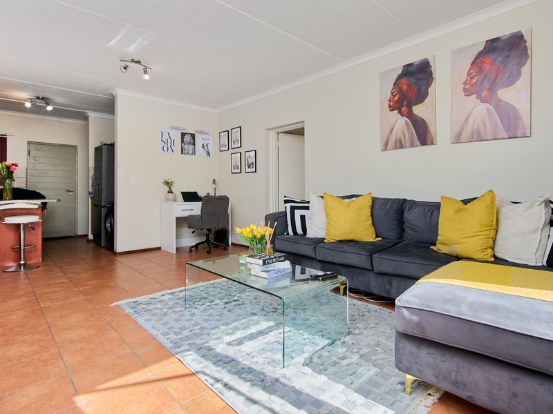 An open-plan living area featuring tiled flooring, a kitchen breakfast bar, and a dedicated workspace nook, creating a functional and connected living space.