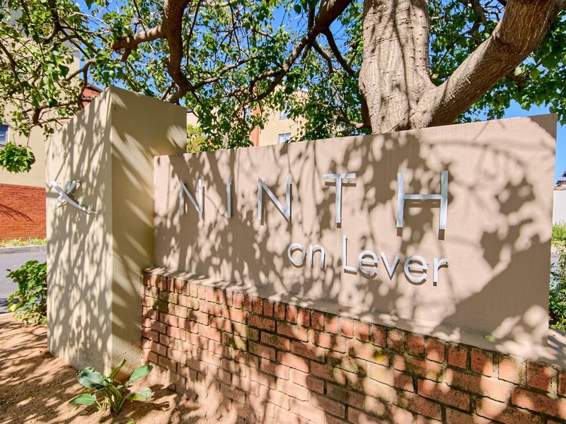 A clear view of the entrance signage for the Ninth on Lever apartment complex, featuring a brick and rendered wall structure.