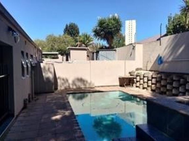 Outdoor pool area featuring a swimming pool, paved surround, and high boundary walls for privacy.