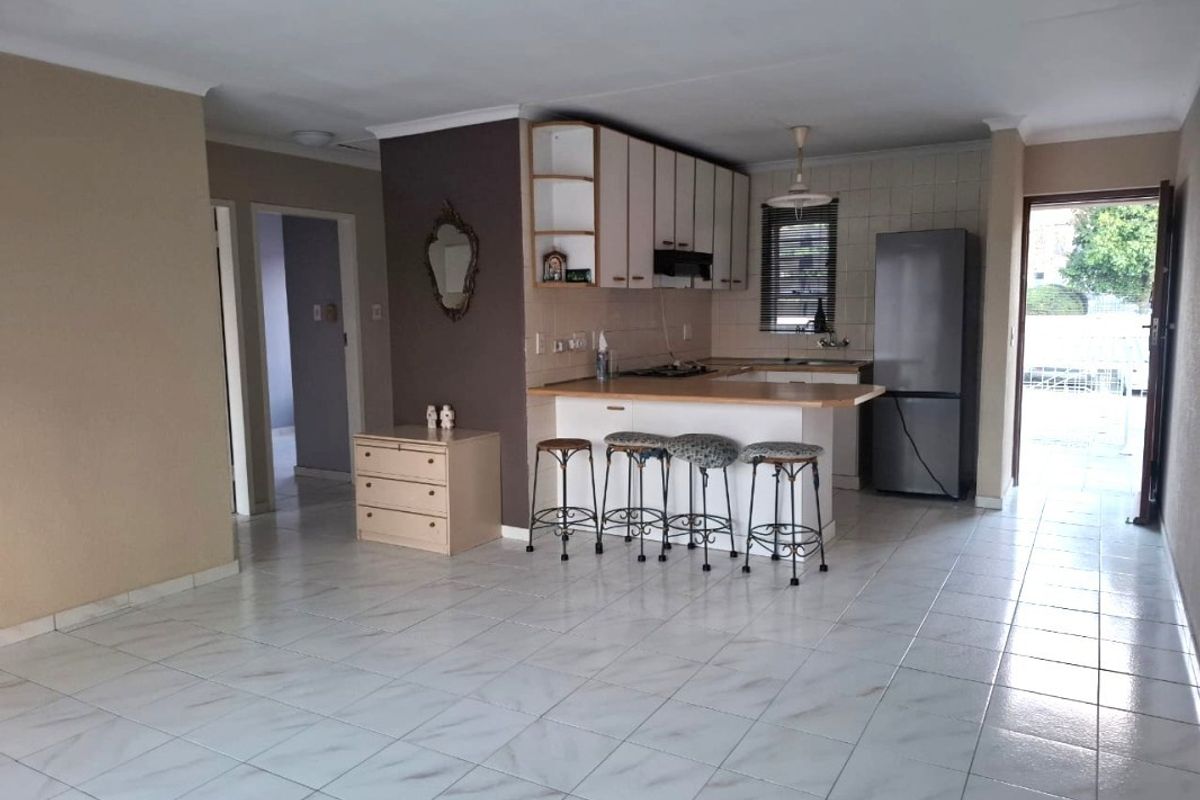 Open-plan living area featuring a functional kitchen with breakfast bar, tiled flooring, and direct access to an outdoor space.
