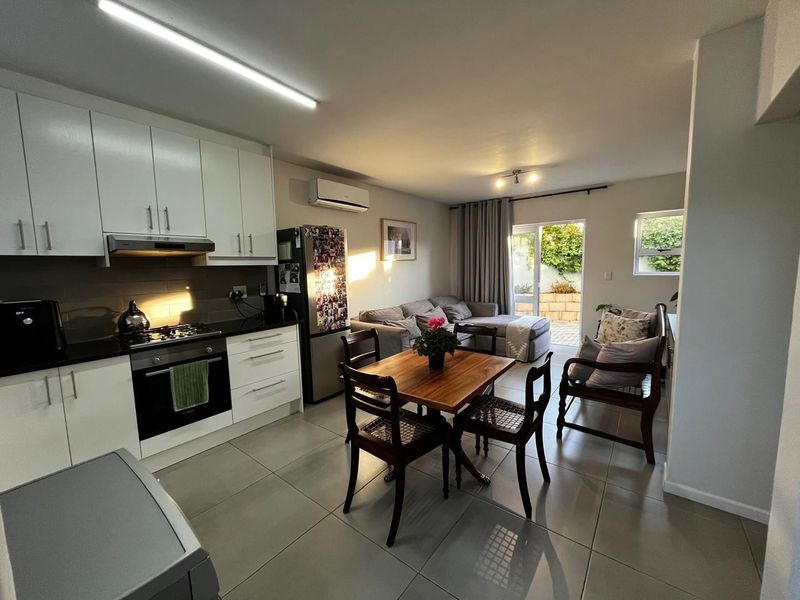 Open-plan living area featuring a modern kitchen with built-in appliances, tiled flooring, and direct access to an outdoor patio through sliding glass doors.