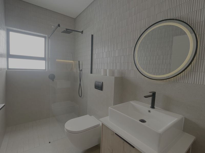 Modern bathroom featuring a wall-mounted toilet, glass-enclosed shower with rain head, vessel sink vanity, and stylish textured wall tiling.