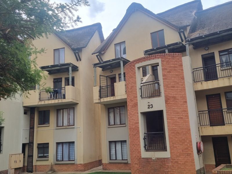 Exterior view of a multi-story apartment complex featuring brick and plaster facade, thatched roofing, and private balconies for each unit.