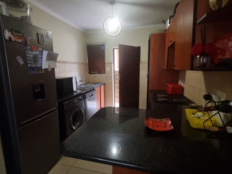 A functional kitchen featuring dark cabinetry, granite countertops, a built-in hob, and tiled flooring with direct access to an exterior area.