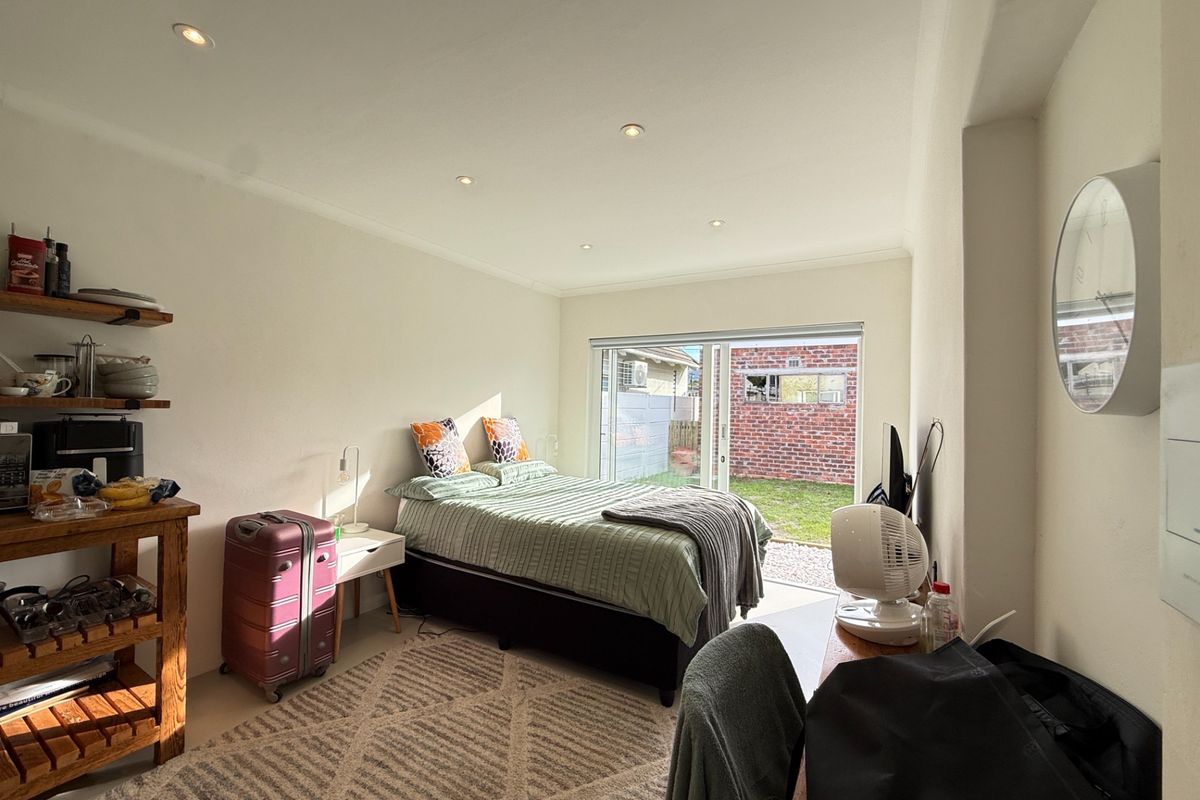 A bright bedroom featuring recessed ceiling lighting and large sliding glass doors that provide direct access to the rear garden area.