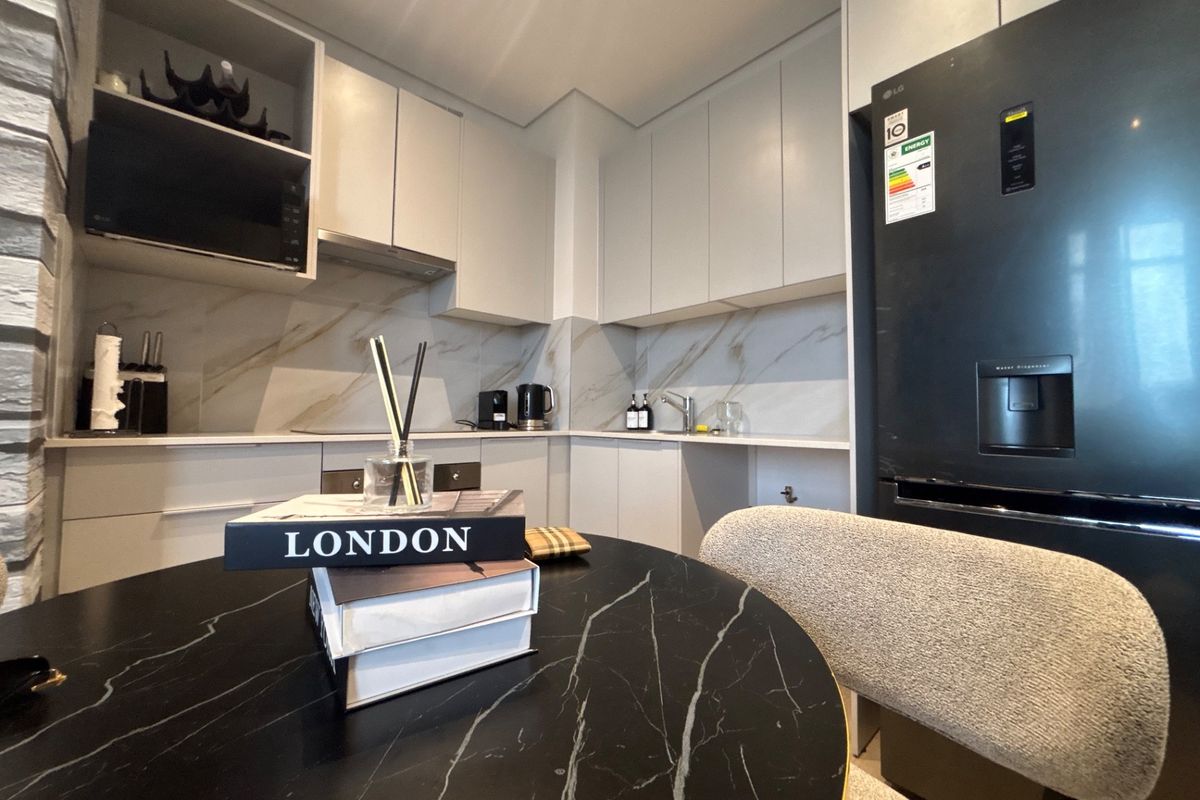 Modern kitchen featuring sleek cabinetry, marble-look splashback, and integrated appliances, creating a clean and contemporary culinary space.