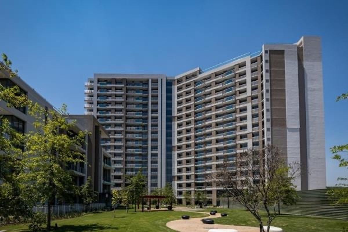 A modern high-rise apartment complex featuring contemporary architectural design, glass balconies, and well-maintained landscaped grounds with pedestrian pathways.