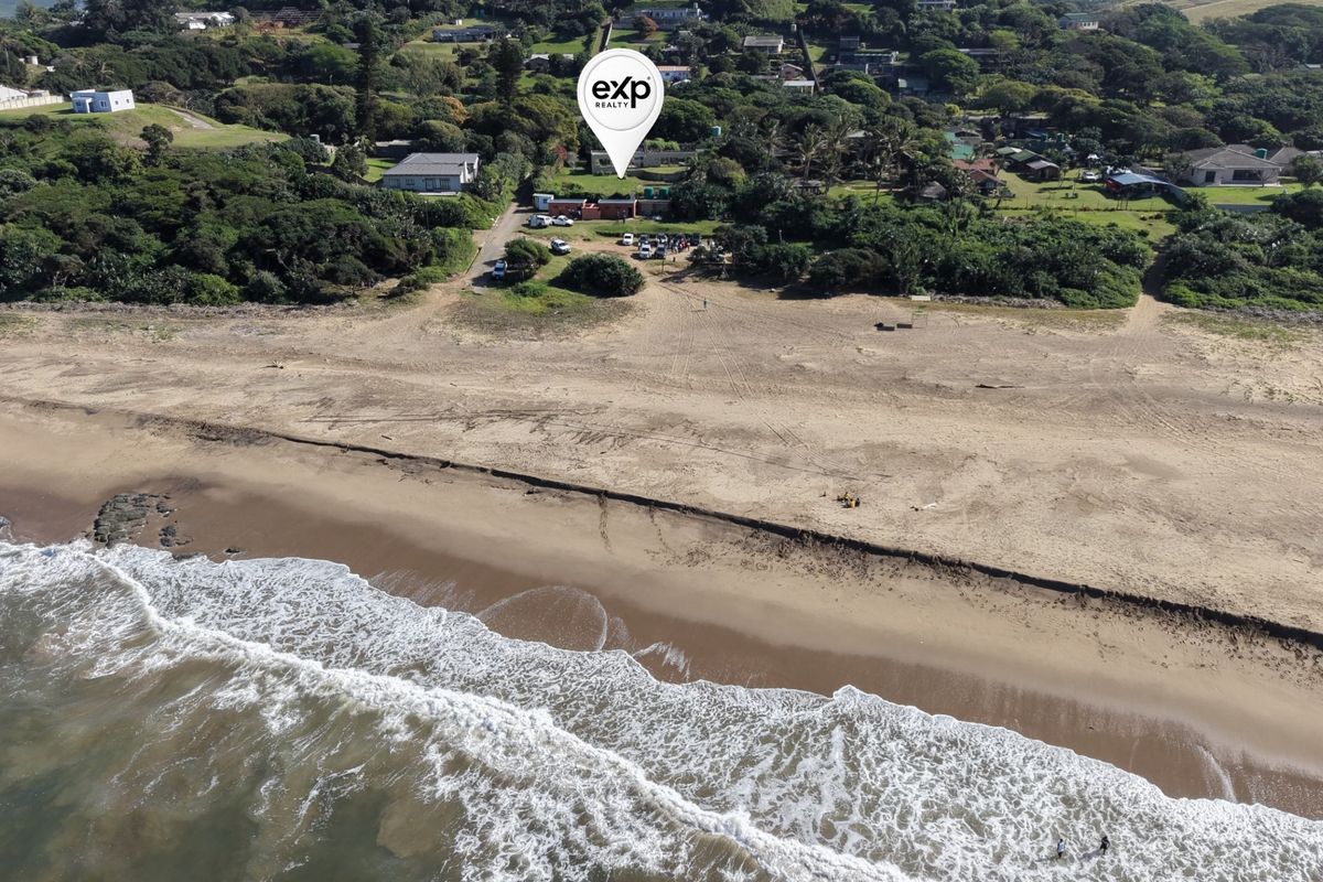 Aerial view of the commercial property situated in a coastal location, featuring direct beach access and proximity to the shoreline.