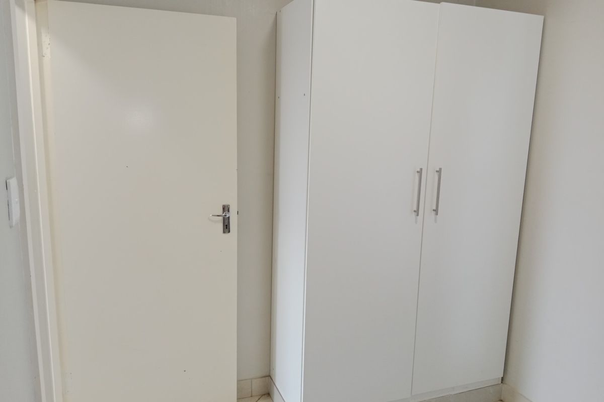 A simple interior space featuring a white door and a built-in white wardrobe with modern handles.
