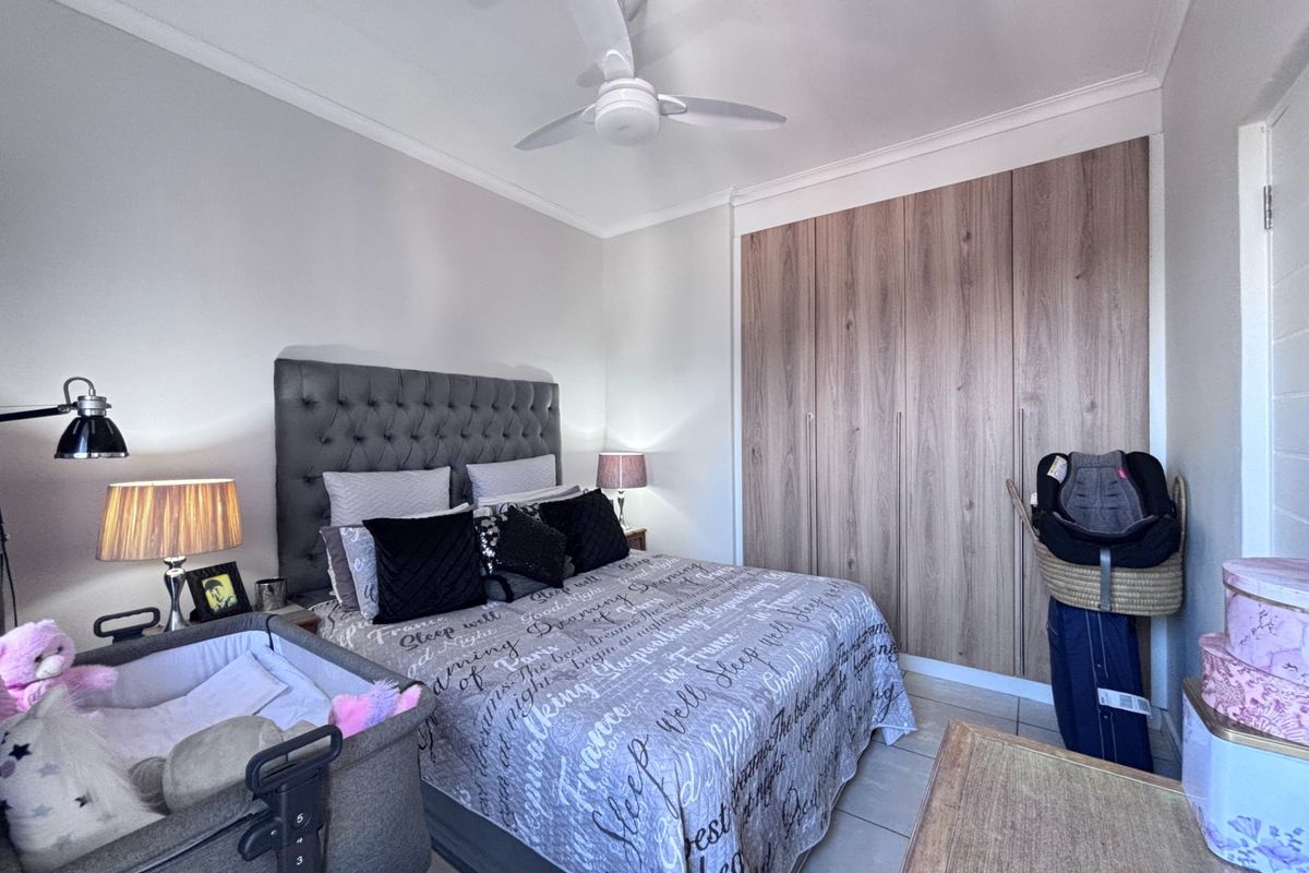 A well-maintained bedroom featuring built-in wooden cabinetry and a ceiling fan, offering a functional and comfortable living space.