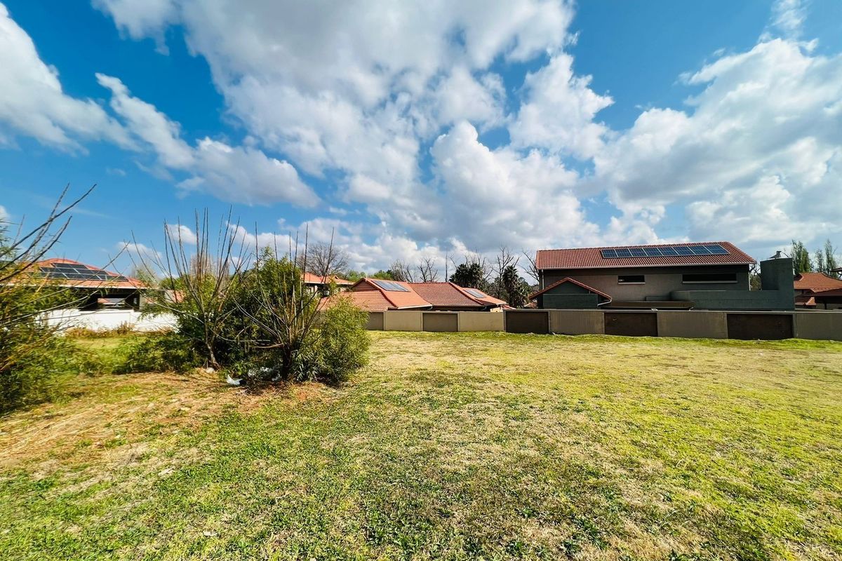 A view of a vacant residential plot featuring established perimeter boundary walls and surrounding residential properties.