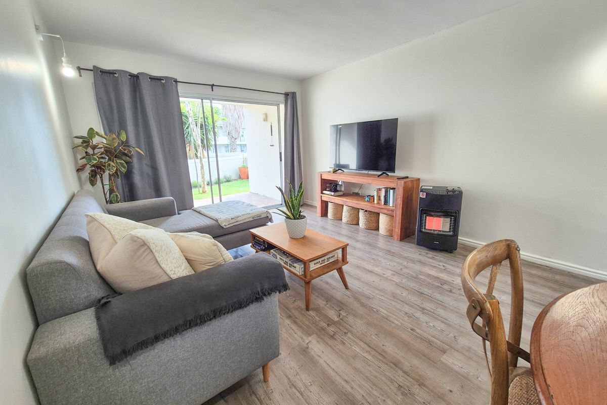 A bright living room featuring modern laminate flooring and a large sliding glass door providing direct access to the outdoor patio area.