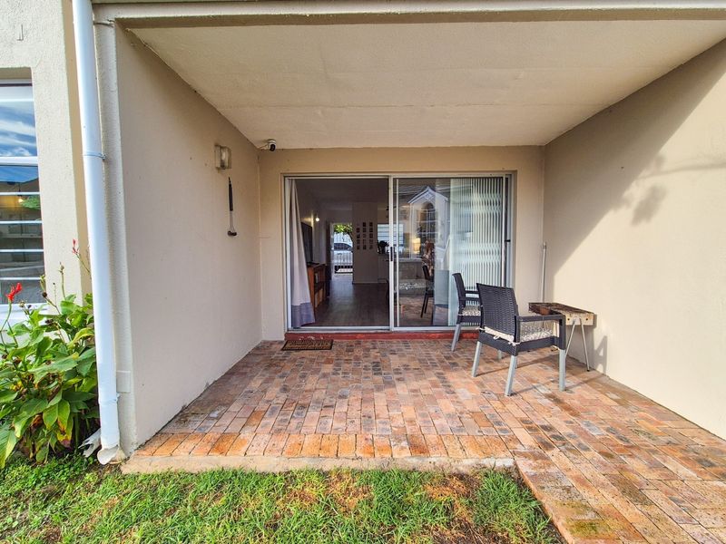 A covered patio area featuring brick paving and a sliding glass door providing access to the interior living space.