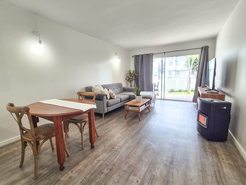 Open-plan living and dining area featuring durable laminate flooring and large sliding glass doors providing access to the outdoor space.